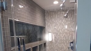 A modern bathroom with a glass shower enclosure, tiled walls, and a pebble-patterned floor. - Pet Friendly- Luxury home- Amazing Views-Lake Travis-25min Downtown Austin (Lakeway)