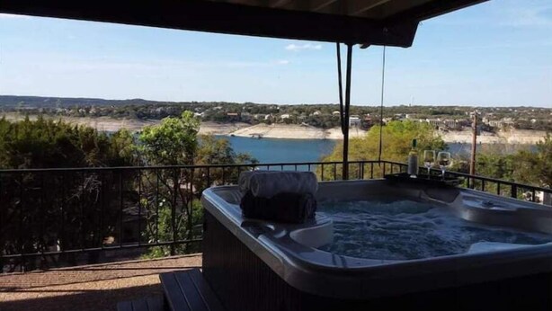 A hot tub on a balcony with a scenic view of a beach and water body. - Pet Friendly- Luxury home- Amazing Views-Lake Travis-25min Downtown Austin (Lakeway)
