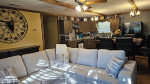 A modern kitchen with dark wooden cabinets, a built-in microwave, and a dining area with a black chair and table. - WATERFRONT-SECLUDED- PET FRIENDLY-COLORADO RIVER-STARGAZER HOME ON RIVER! (Lampasas)
