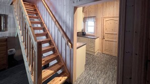 Una escalera de madera que conduce a una cocina con armarios de madera y un ventanal.