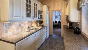 Una cocina con armarios blancos, encimera de granito, cafetera y hervidor.
