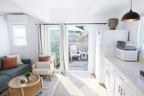 A modern living room with a sofa, armchair, coffee table, and a kitchen area with a microwave and refrigerator. - Boho Bungalow+walkable+stocked kitchen+BBQ+private (San Luis Obispo)