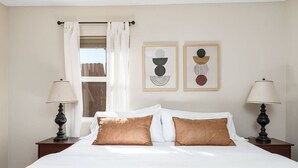 A hotel room with a bed, two bedside lamps, a window with curtains, and two framed wall art pieces. - 2Bed 2 Bath Cottage onMicro Resort near Downtown (Paso Robles)