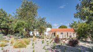 Un edifici amb teules vermelles al sostre, envoltat de plantes i arbres diversos.