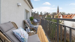 A balcony with wicker furniture, a view of a church steeple, and a clear sky. - Petit Repit by Grand Apartments (Sopot)