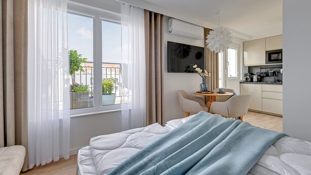 A modern hotel room with a bed, a dining area, and a kitchen. - Petit Repit by Grand Apartments (Sopot)