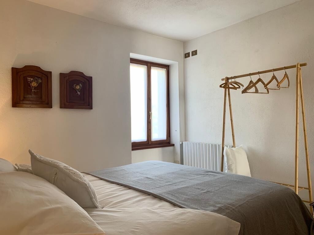 Une chambre avec deux lits, une fenêtre, un radiateur et un porte-manteau en bois.
