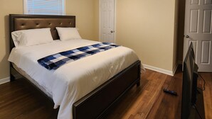 Une chambre à coucher avec un lit, un ventilateur de plafond, une télévision et une porte.