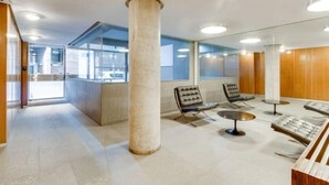 Um interior moderno com um balcão de recepção, área de estar e grandes janelas.