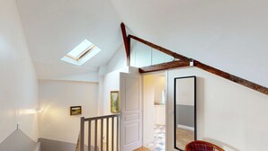 Un escalier avec une rampe en bois, une porte blanche et un petit tableau encadré accroché au mur.