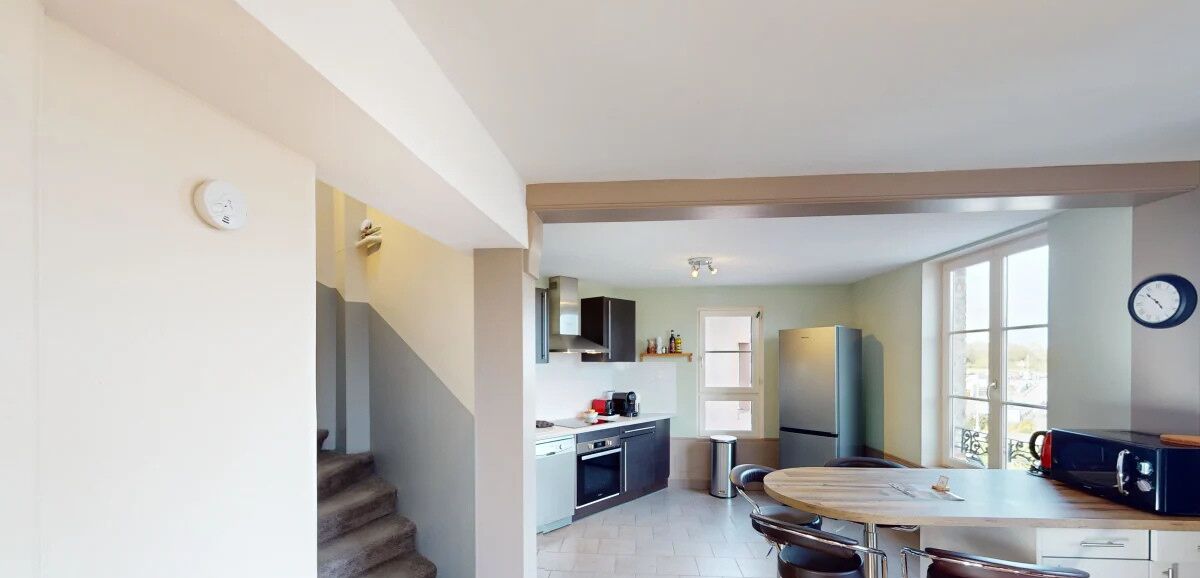 Una cocina moderna con comedor, electrodomésticos integrados y una escalera que sube a otro nivel.