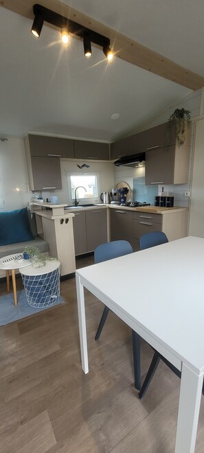 A modern kitchen with wooden cabinets, a dining table, and a blue chair.