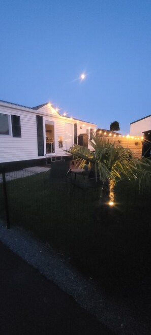 A residential area with a white house, a patio with a table and chairs, and a cactus plant.