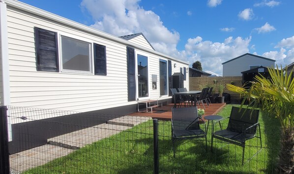 A mobile home with a patio area, a fenced yard, and a neighboring building labeled "Lake House".