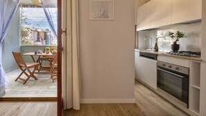 Eine moderne Küche mit weißen Schränken, ein Essbereich mit Holzsesseln und ein Blick durch eine Glastür.