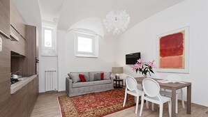 Een moderne woonkamer met een bank, eettafel, stoelen, een televisie en een groot abstract schilderij.