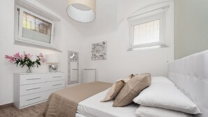 Een slaapkamer met een bed, dressoir, raam en radiator.
