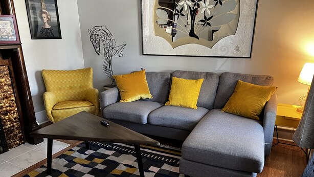 A living room with a grey sofa, yellow cushions, a patterned rug, and artwork on the walls. - Fenced in backyard. Great pet property.  Monon Trail access. (Indianapolis)