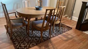 A dining area with a round wooden table, six chairs, and a patterned rug. - Fenced in backyard. Great pet property.  Monon Trail access. (Indianapolis)