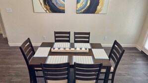 A dining room with a rectangular table, six chairs, and two abstract paintings on the wall. - FIFA 2026‼️ Modern 3 bedroom home for stay! AT&T Stadium, Globe Life Field. (Mansfield)