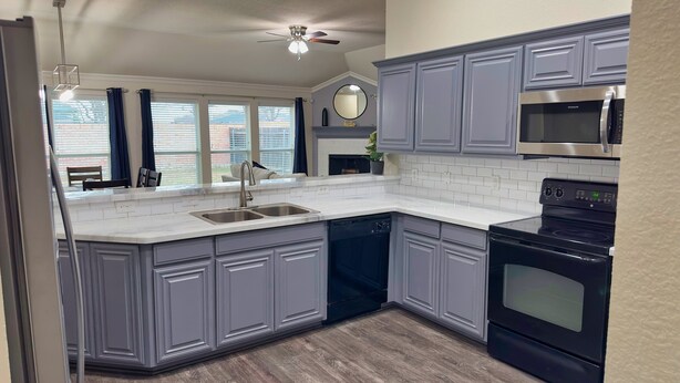 A modern kitchen with grey cabinets, a stainless steel sink, and a black stove. - FIFA 2026‼️ Modern 3 bedroom home for stay! AT&T Stadium, Globe Life Field. (Mansfield)