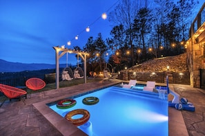 Ein Pool im Freien mit einer Pergola, roten Stühlen und einer Steinmauer.