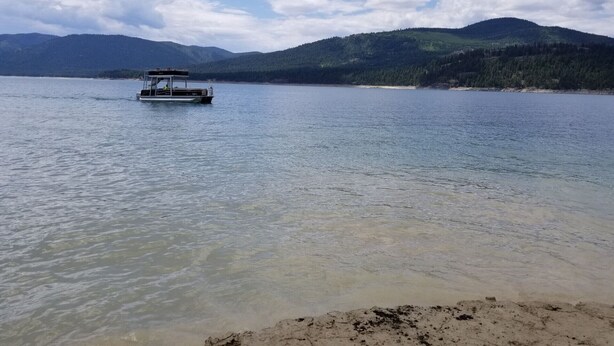 Un barco en un lago tranquilo con montañas al fondo.