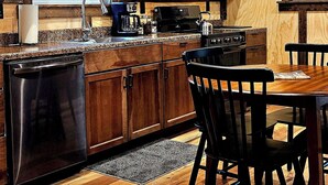 Una cocina con armarios de madera, un microondas, un lavavajillas y una mesa de comedor con sillas.