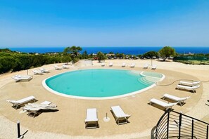 Relax by the oceanfront pool surrounded by lounge chairs and lush greenery.