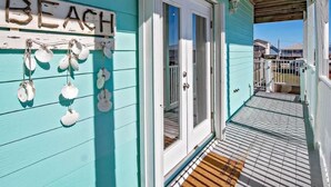 A turquoise building with a sign reading "BEACH" and a wooden deck leading to a door. - 5BR Beach House+Steps To Beach+Balcony Gulf Views+Firepit+Elevator+Dog Friendly (Gulf Shores)