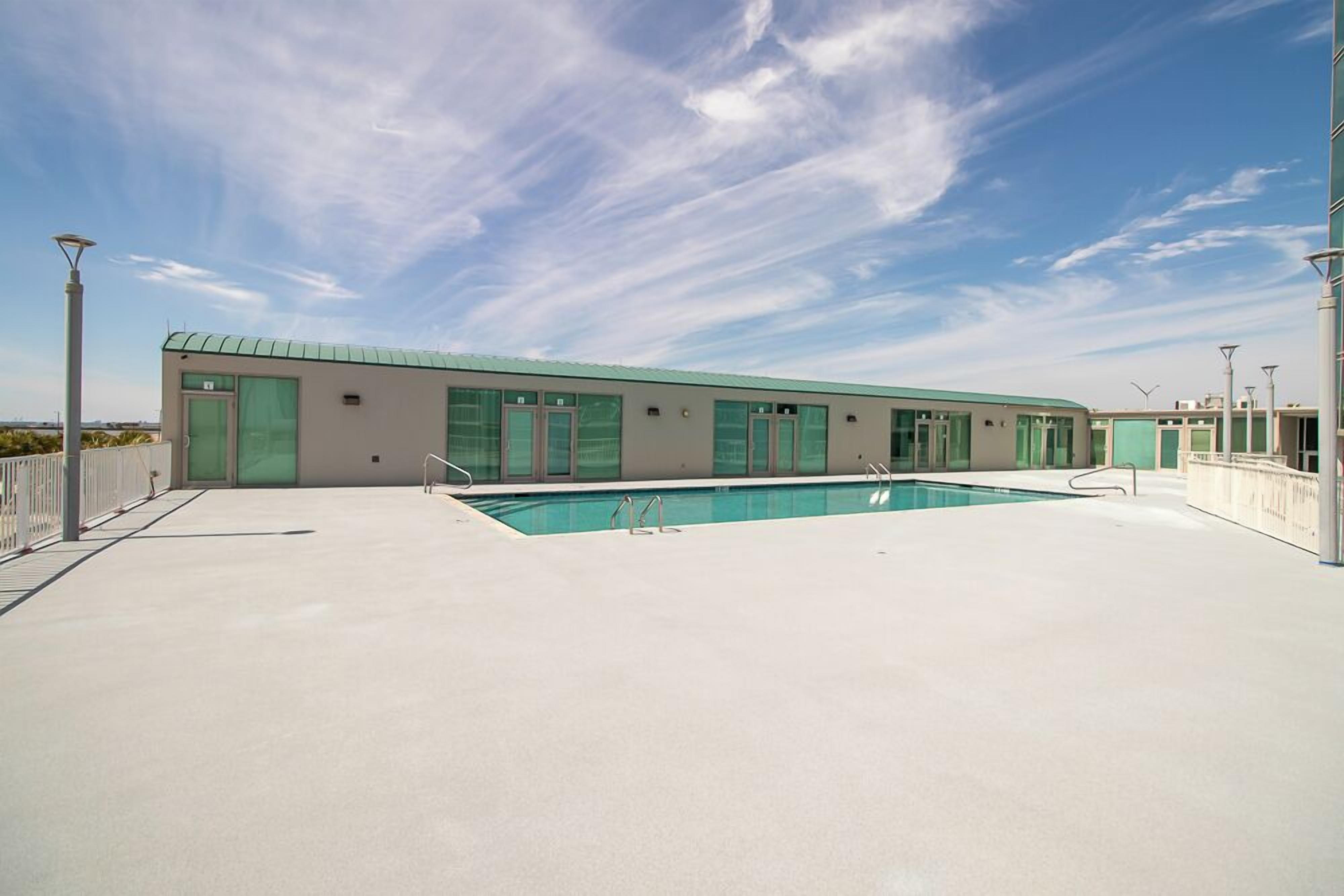 A modern building with a pool, large windows, and a flat roof.