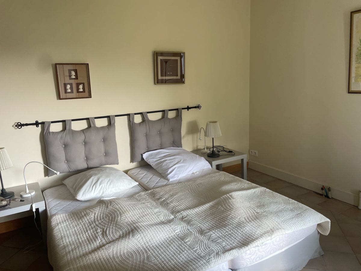 A double bed with a quilted cover, two bedside tables with lamps, and a headboard with a decorative design.