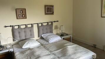 A double bed with a quilted cover, two bedside tables with lamps, and a headboard with a decorative design.