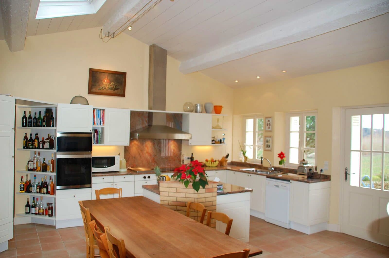 A spacious kitchen with a central island, built-in appliances, and a dining area with a wooden table and chairs.