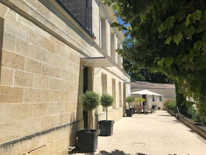 A courtyard with a stone building, potted plants, and outdoor furniture.