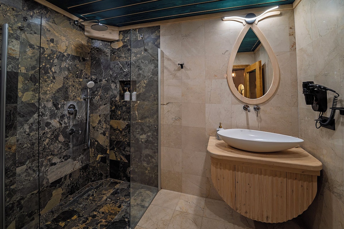 A bathroom with a glass-enclosed shower, a wooden vanity with a white sink, and a mirror above the sink.