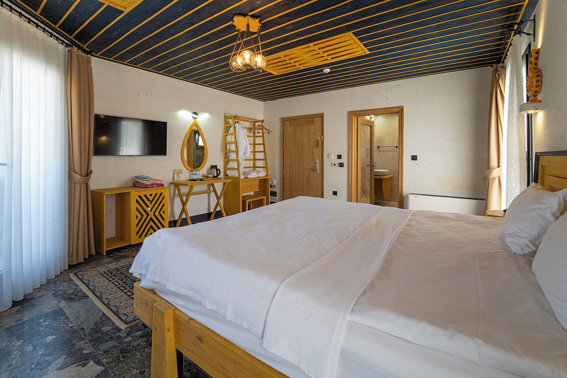 A hotel room with a bed, a desk, a mirror, a wardrobe, and a television.