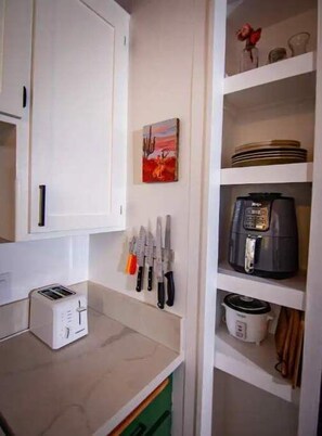 Una cocina con armarios blancos, un tostador, una cafetera y un soporte para cuchillos.