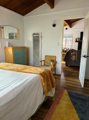 Un dormitorio con cama, cómoda, silla y puerta que da a otra habitación.