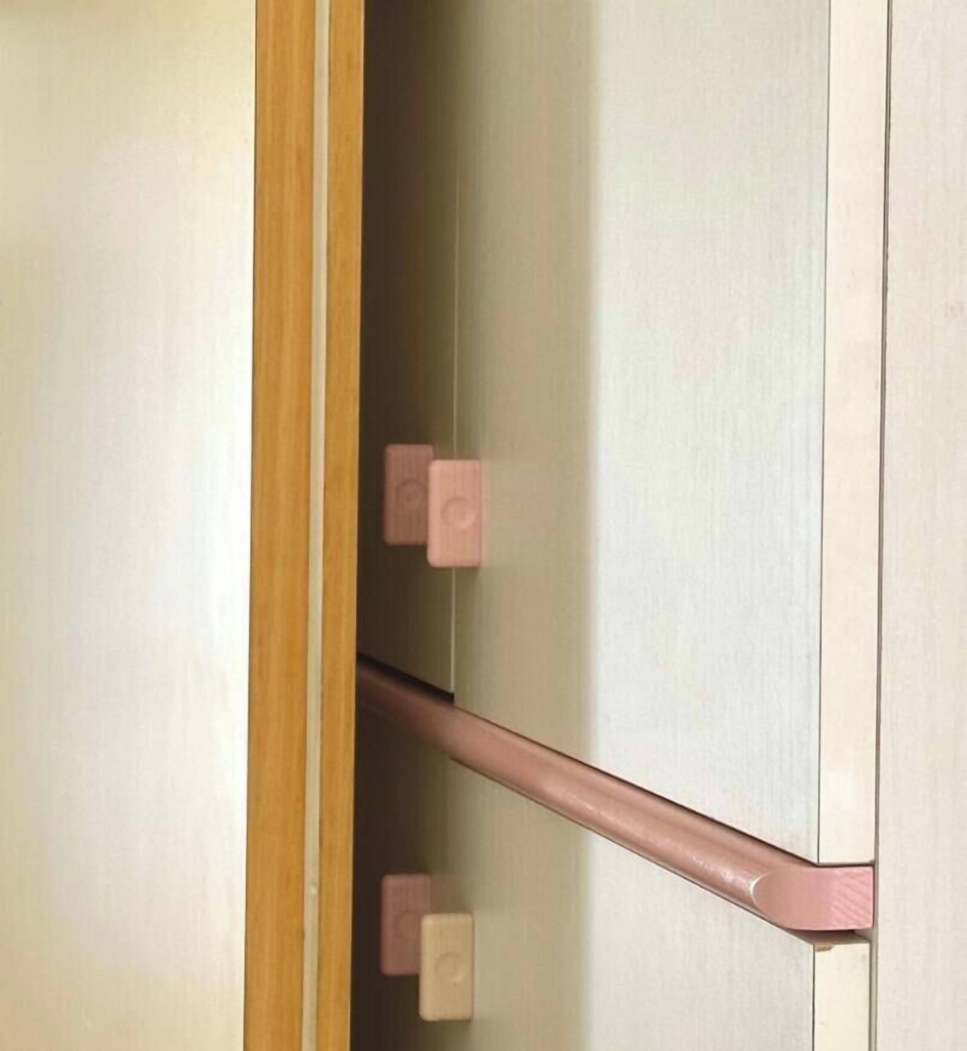 A wooden door with a handle and a pink towel rack.