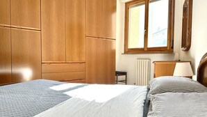 A bedroom with a bed, wooden wardrobe, window, radiator, and bedside table. -  P026 - Porto Recanati, three-room apartment with sea view 100m from the beach (Porto Recanati)