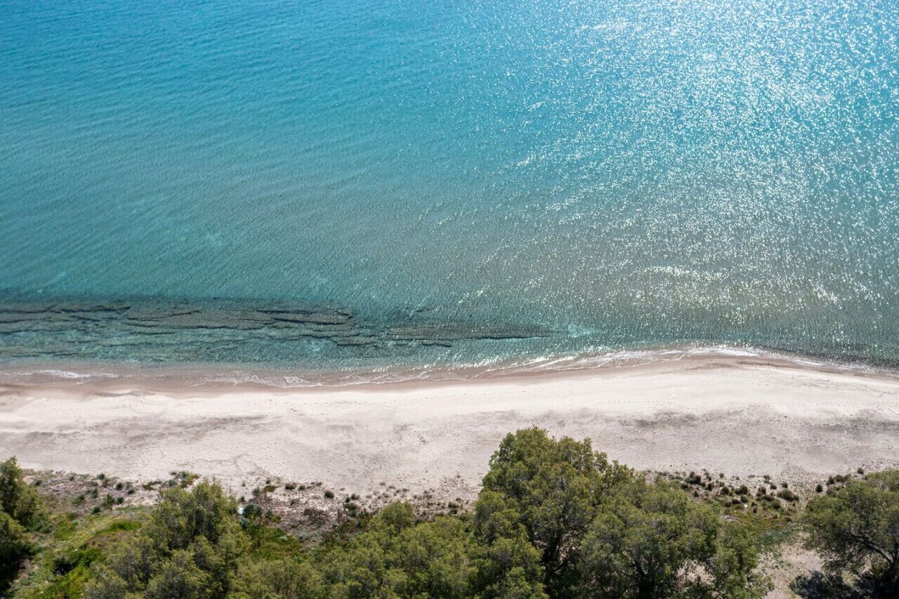 A beach with clear turquoise water and a sandy shore.