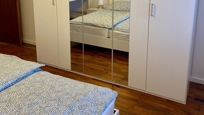 Et soveværelse med en seng, et garderobeskab og et spejl.