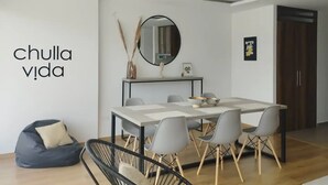 A modern dining area with a white table, grey chairs, and a black-framed mirror above. - Cozy and new Condo. La Carolina 10th floor Unbeatable view.  (Quito)