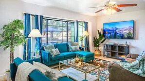 A living room with a teal sofa, a coffee table, and a television.