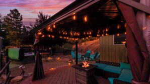 An outdoor patio area with a fire feature, seating, and string lights.