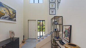 A modern interior with a staircase, a door leading outside, and a wall with framed artwork. - Jacaranda - Revel in the Panoramic Views (Nelson)
