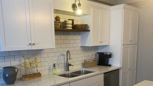 A modern kitchen with white cabinets, a marble countertop, and a built-in dishwasher. - Spacious Navarre Home (Navarre)