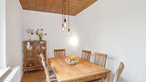 A dining area with a wooden table, chairs, a cabinet with glass doors, and hanging light fixtures. - 3 bedroom lovely home in Saal (Saal)