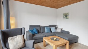 A living room with a grey sectional sofa, a wooden coffee table, and a painting on the wall. - 3 bedroom lovely home in Saal (Saal)
